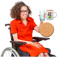 Smiling person sitting in a wheelchair, wearing a bright red outfit and glasses, holding a glass of water. Next to the glass are a mug of tea and a digestive biscuit, suggesting a drink break with fluids and a snack.