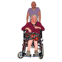 A man standing behind an elderly woman in a wheelchair, both smiling.