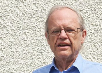 Photograph of Jeremy Marchant, wearing a blue shirt and glasses