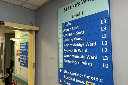 Photograph of blue sign on grey wall at St Luke's entrance at Cheltenham General