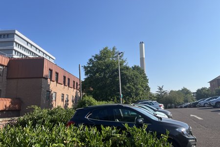 Photograph showing the outdoor car park behind Gallery Wing with several parked cars shown against greenery and a blue sky
