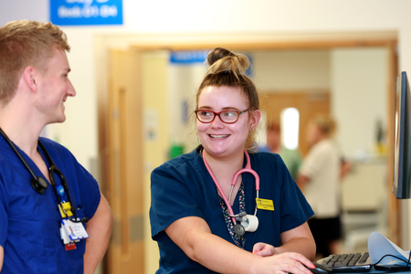 Clinicans speaking on ward in front of computer