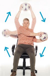 A woman doing seated exercises with a football, moving it around in a circle in front of her