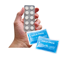 A hand holding a blister pack of ten white round tablets and two cold packs