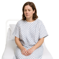 Woman sitting on a hospital bed wearing a gown.