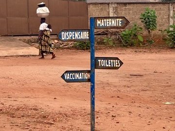 Signpost with directional signs for maternity, dispensary, toilets and vaccination in a health facility courtyard