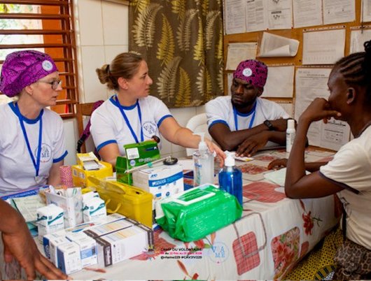 People seated around a table with medical supplies during a discussion in a clinic room
